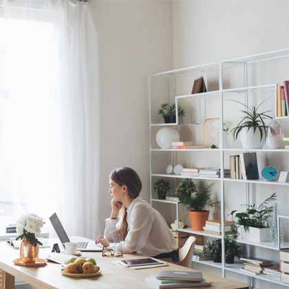 girl sitting at her desk working with beautifully organized shelf behind her