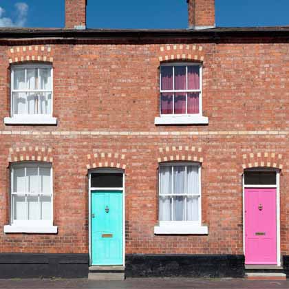 brick building with a pink door and two different green doors