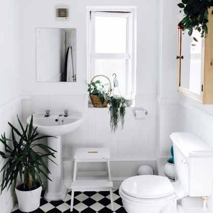tiny bathroom with checkered tile and lots of plants