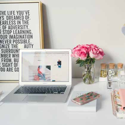 organized working from home desk with flowers and laptop on it
