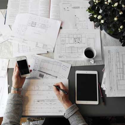 person at desk with smart phone, bills and papers doing bills