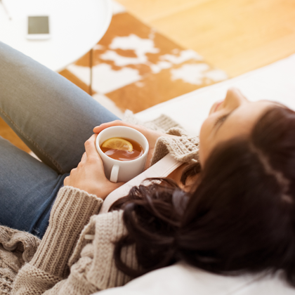 Ways to unwind - woman relaxing on a couch with a cup of tea