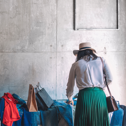 girl wearing hat in green skirt shopping looking through clothes