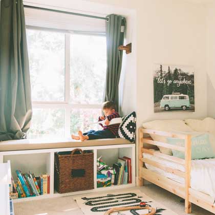 litte boy sitting in organized bedroom
