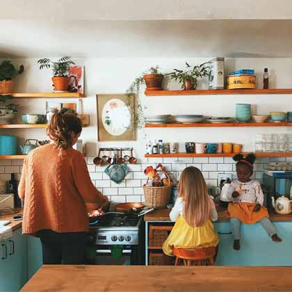 mom and two daughters cooking in an open shelf kitchen