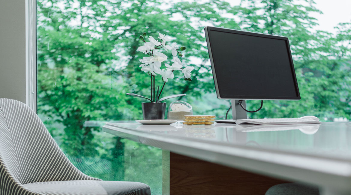An orchid on a desk next to a computer.
