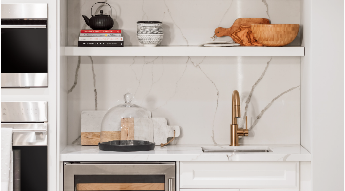 A kitchen shelf with a kettle, some books and some bowls.