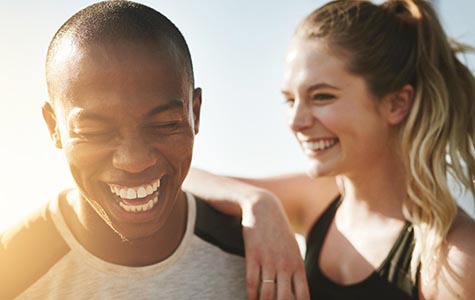 A couple laughs together as they stop to take a break from their morning run.