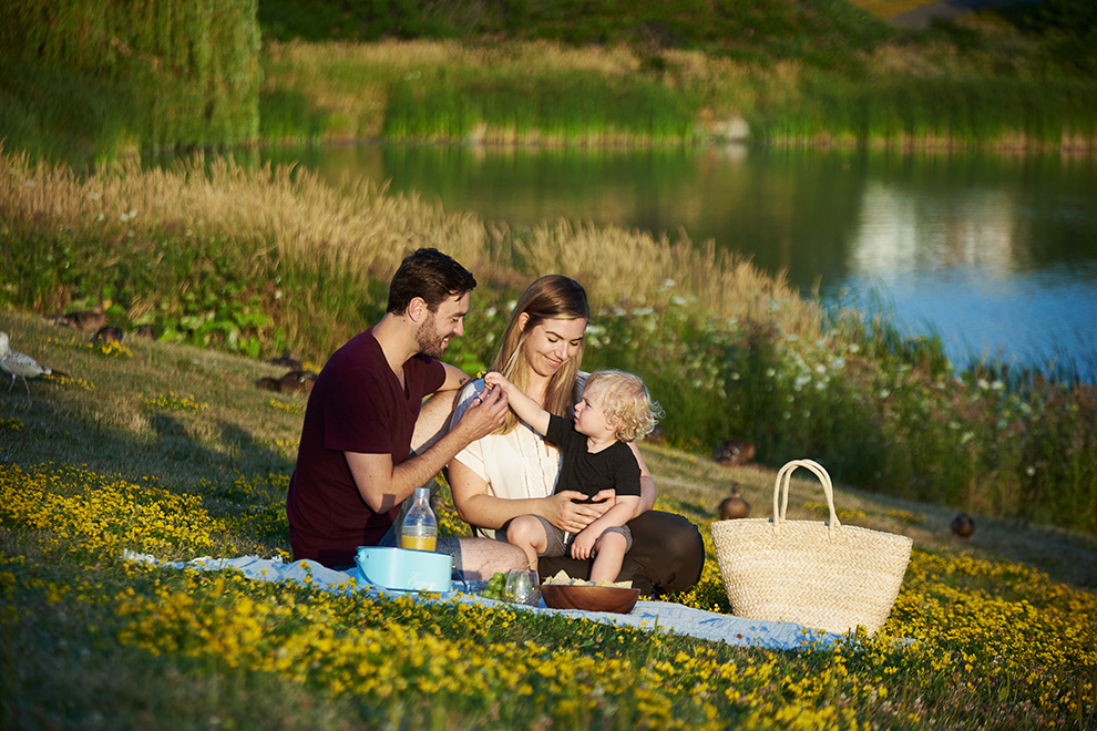 Young family having a picnic beside a lake. New release of homes for sale at Avalon Aquaview, Minto Communities.