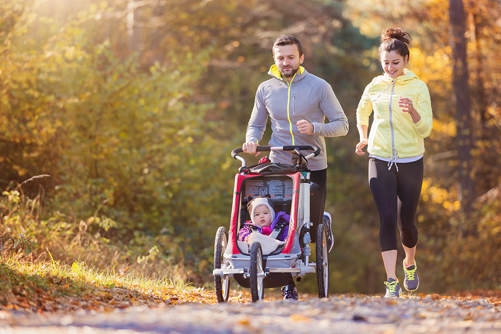 Couple and young child in a running stroller out for a run. Things to do in Barrhaven near Quinn's Pointe.