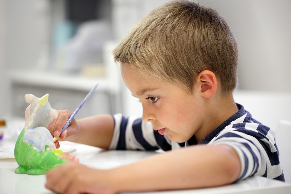 Boy painting ceramics