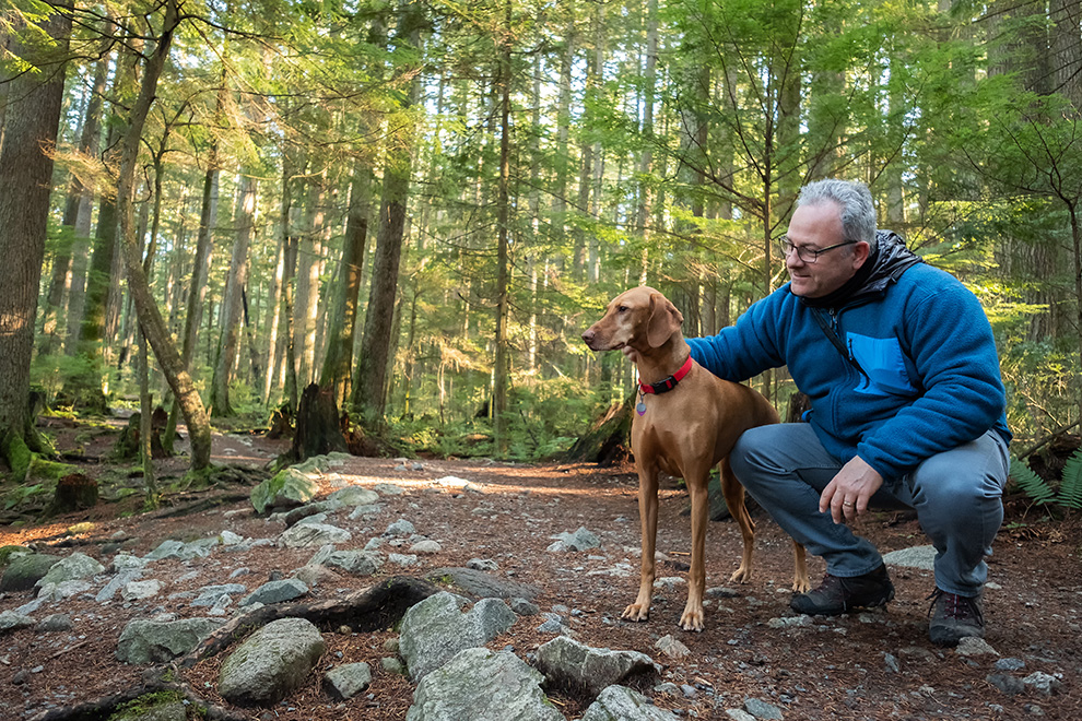 Man petting his dog in woods