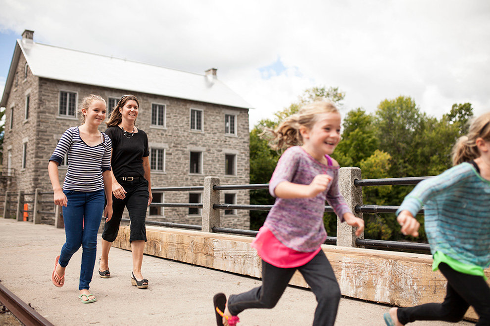 Mother and three daughters walking over bridge. Lifestyle in Mahogany, Manotick.