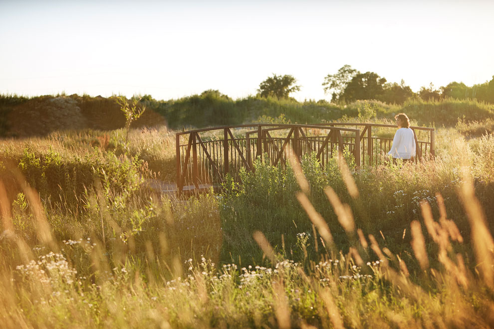 Woman walking over bridge in nature reserve. Discover nature and things to do outside in Manotick near Mahogany.