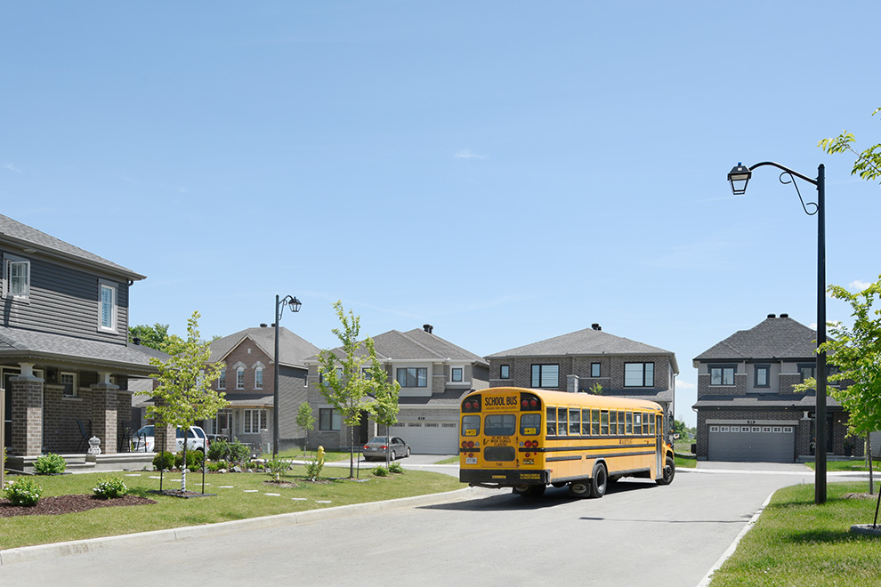 A school bus drives through the sunny streets of Quinn’s Pointe.