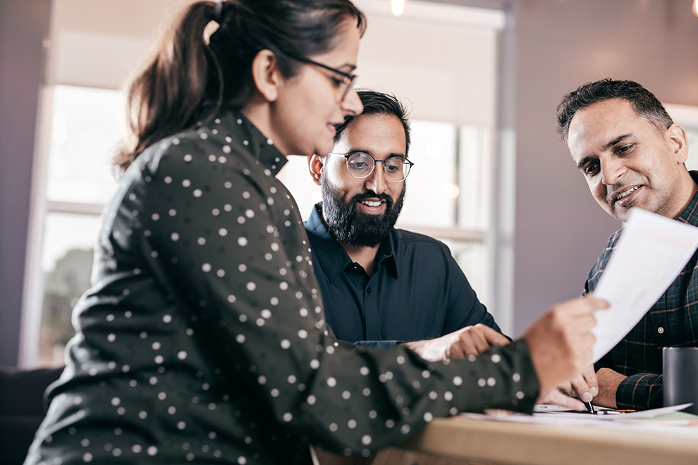 A couple sits together with their financial advisor going over financing paperwork.