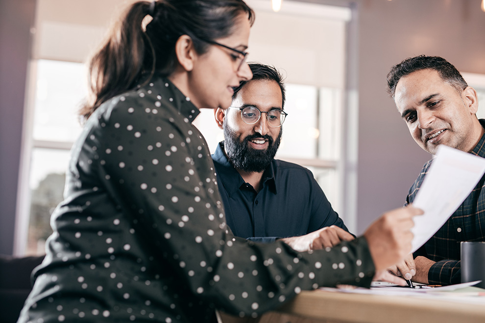 A couple sits together with their financial advisor going over financing paperwork.