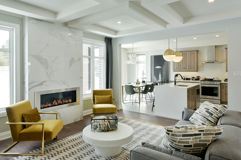 An interior shot of the Elderberry Single Family Home showing the stylish great room and marble fireplace feature and the adjoining open-concept kitchen.