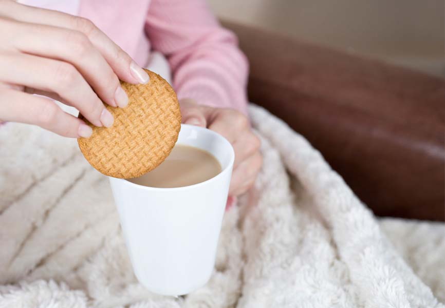 A woman dipping her cookie in a cup of tea