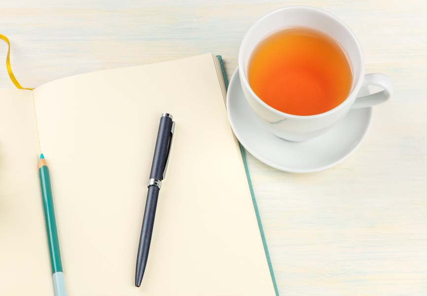 a cup of tea next to a notebook