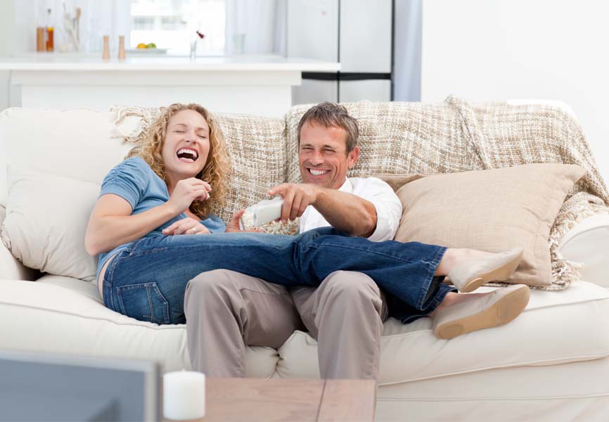 A couple watching a funny show in their living room 