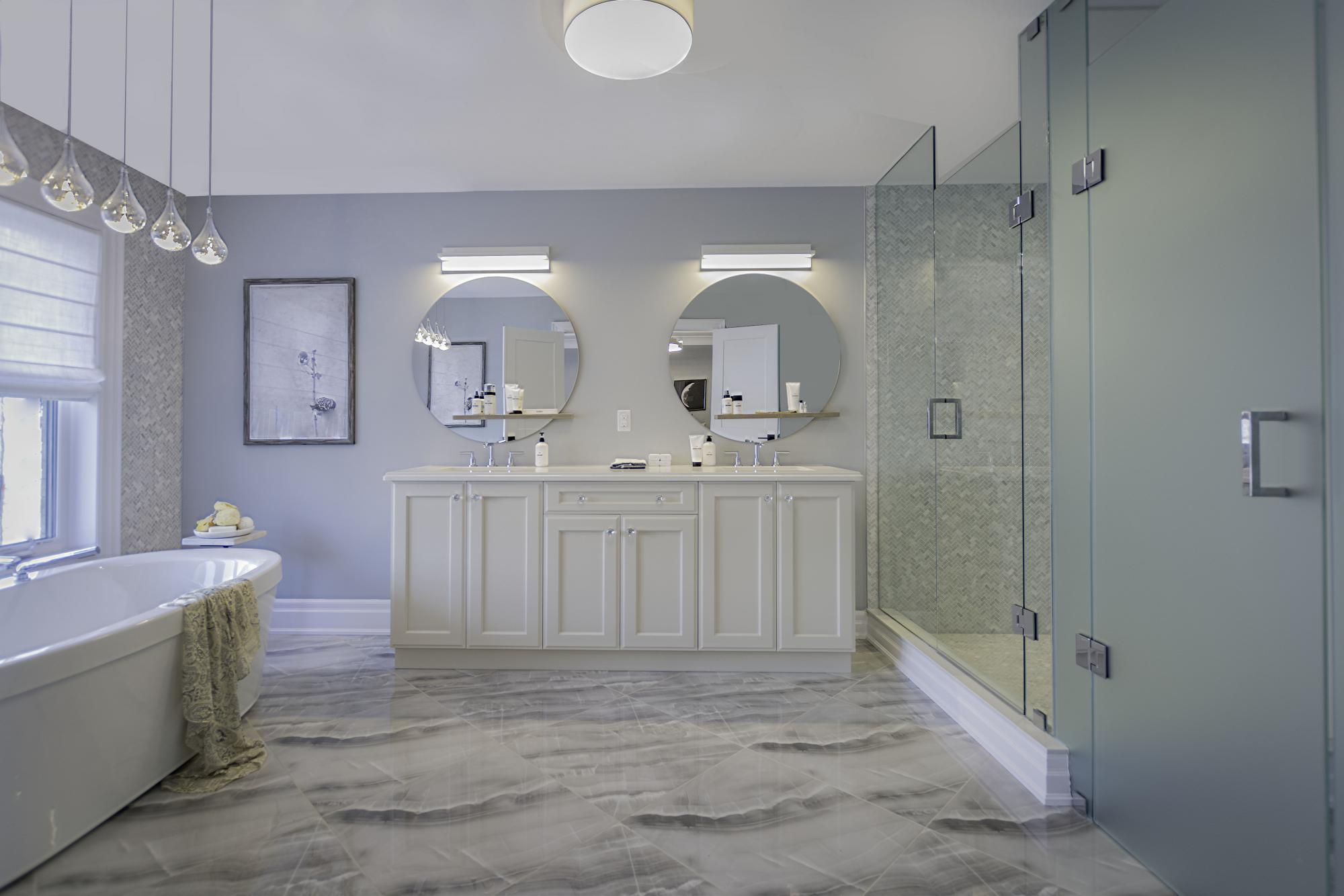 Beautiful white bathroom with white marble floors, a deep soaker tub and a large shower. Two mirrors with two sinks 