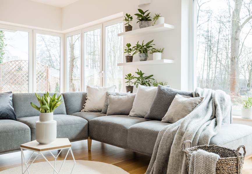 blue sofa with a pile of pillows and a throw on the end of it