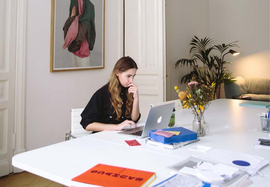 Girl sitting at a table looking at her laptop