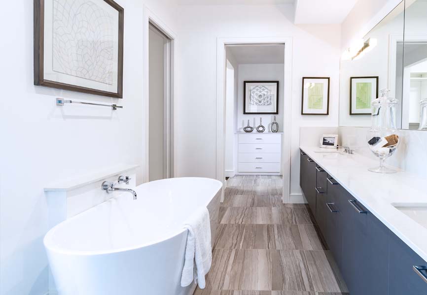 white bathrub with light flooring and blue cabinets 