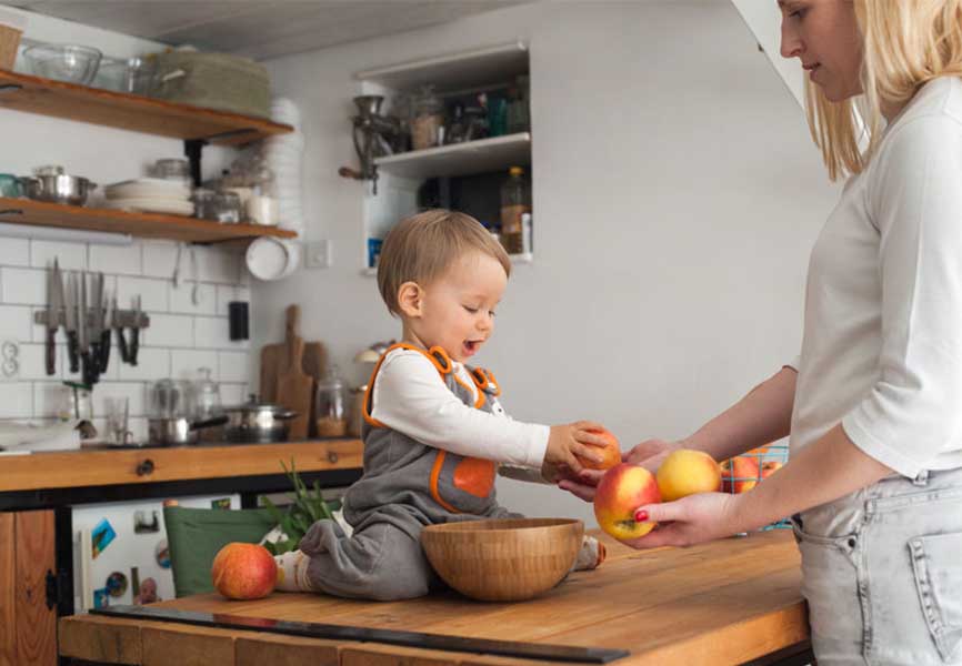 Mother handing her baby apples