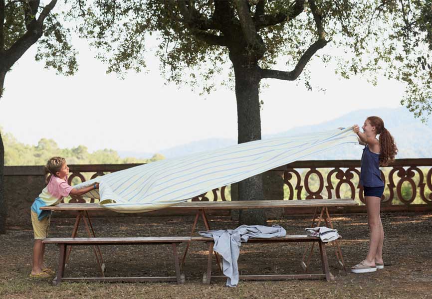 Young girl and boy putting a sheet over a bench