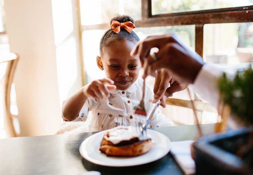 Young girl reaching for a cinnamon bun