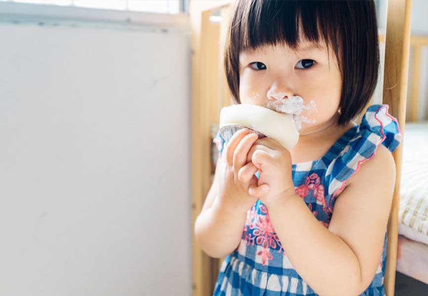 Little girl messily eating cake
