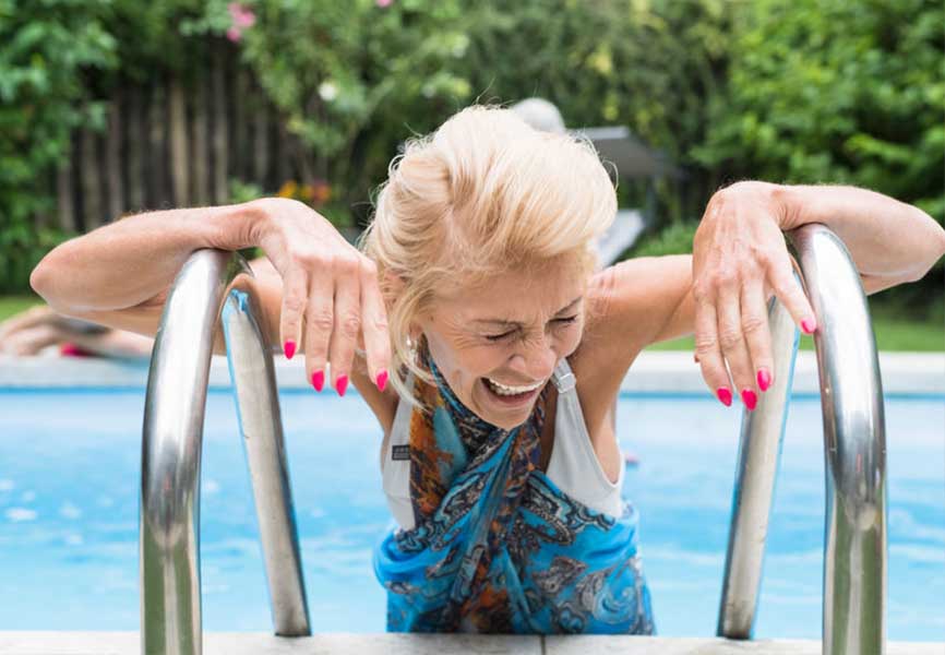 Older lady laughing on a pool ladder