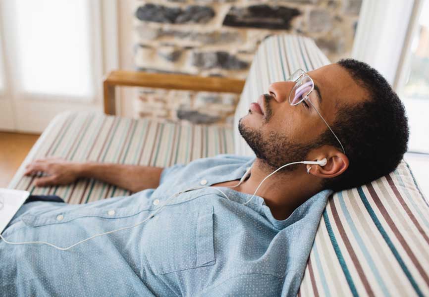 Man sleeping on a couch, with earbuds 