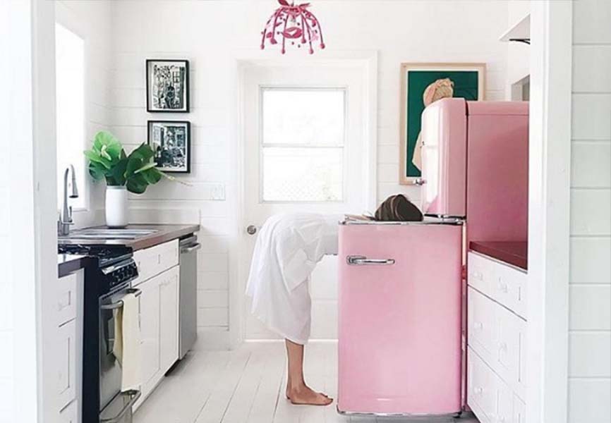 Woman looking in vintage pink fridge