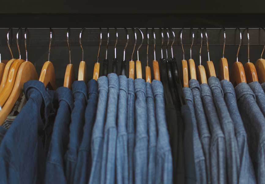 Different shades of blue shirts hanging on a rack