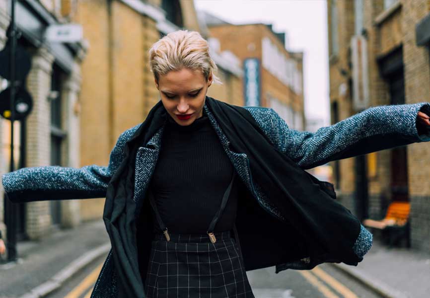 Woman wearing a patterned coat with her arms out