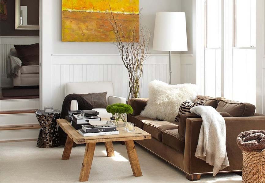living room with bright yellow painting, cozy couch blankets and a wooden coffee table