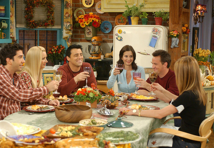 The cast of Friends sitting at Monica's table eating