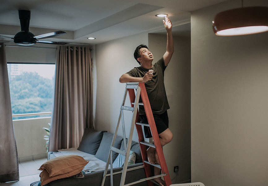 Man installing potlights standing on ladder