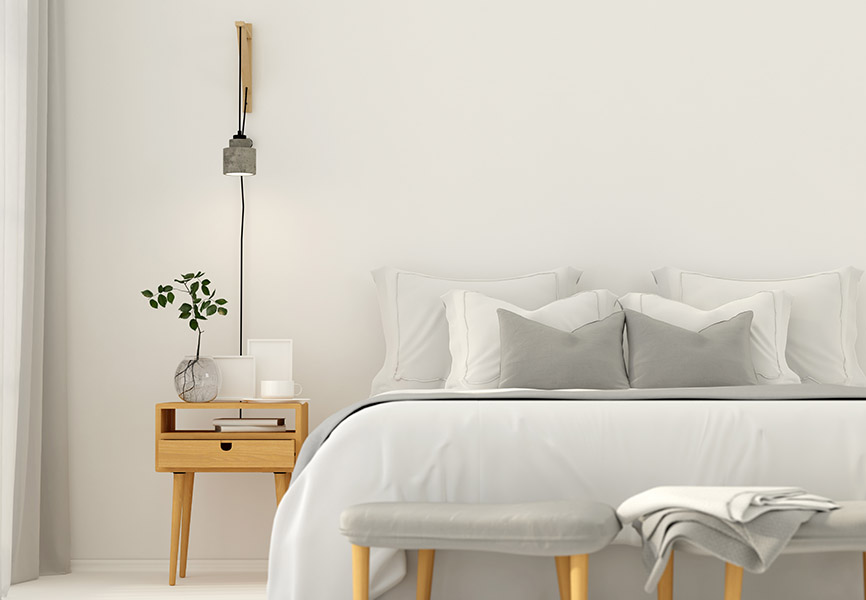 Plug-in concrete sconce beside white bed