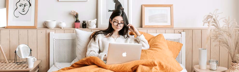 Girl sitting in her bed on her macbook