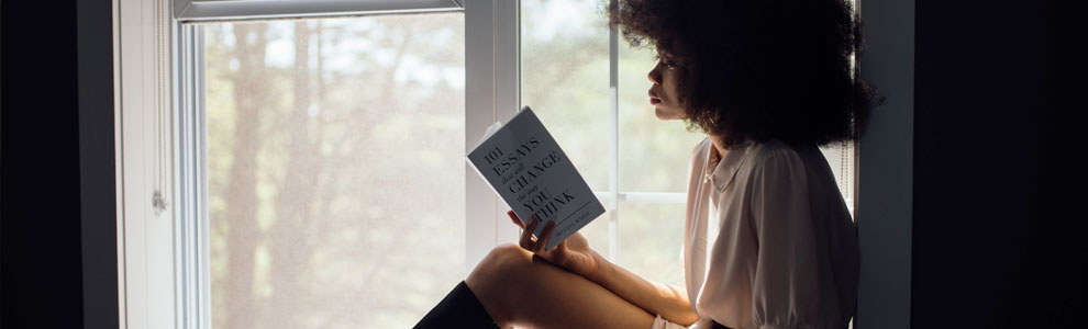 Woman sitting by the window and reading a novel