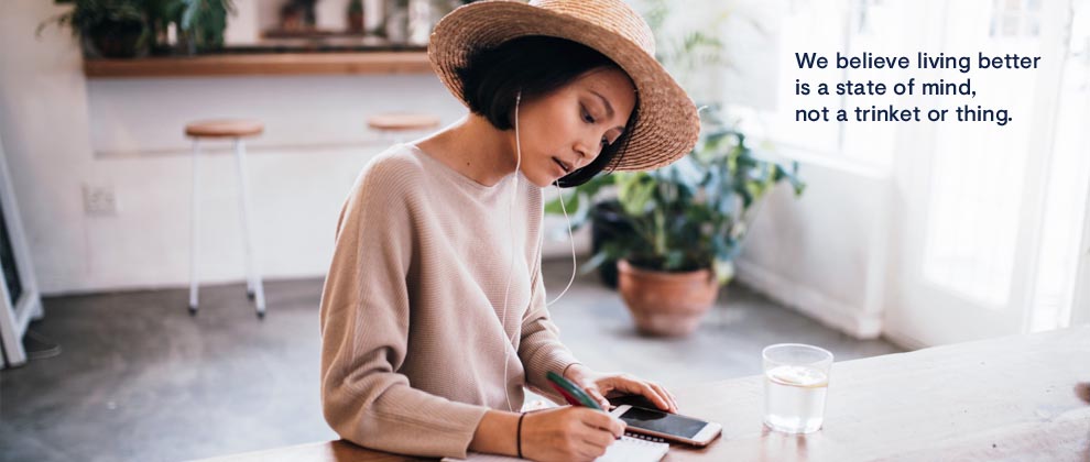 woman at a cafe on her phone and making notes
