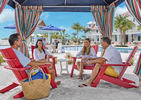 Two couples sitting under a beach cabana. New homes for sale near downtown Naples. The Isles of Collier Preserve by Minto Communities.