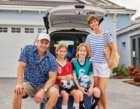 Soccer family outside their car parked inn front of a Westlake home, Minto Communities. New homes for sale in Palm beach County, Florida.