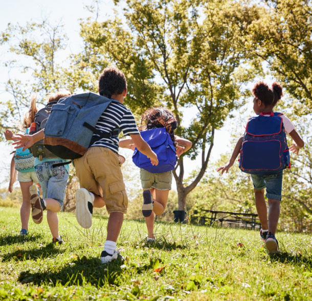 Children running in the park with backpacks. The Heights of Harmony in Oshawa.