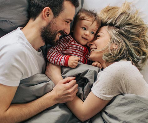 A family smiling in bed. New homes in Courtice by Minto Communities.